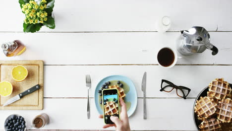 top view man photographing breakfast using mobile phone belgian waffles and coffee hands from above - red epic dragon