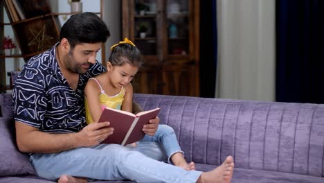 una dulce niña leyendo un libro de cuentos mientras está sentada en el regazo de su padre - crianza feliz, un libro interesante