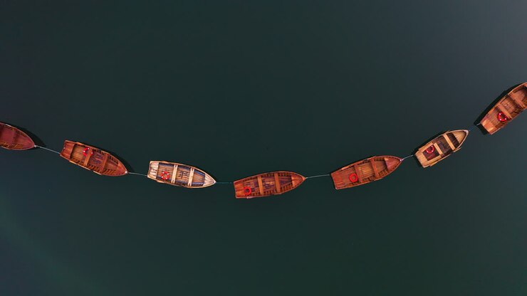 Veduta aerea sopra barche a remi sul Lago di Braies nelle Dolomiti, Italia - vista a volo d'uccello, ripresa da drone