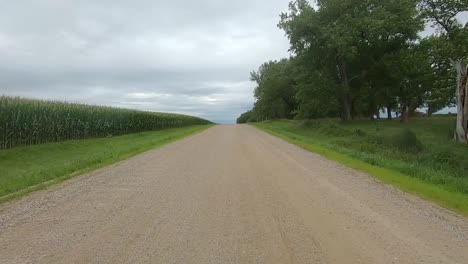 POV-Driving-through-rural-South-Dakota-on-gravel-road,-past-trees-and-fields