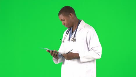 Doctor-Afroamericano-Escribiendo-Notas-Contra-Pantalla-Verde