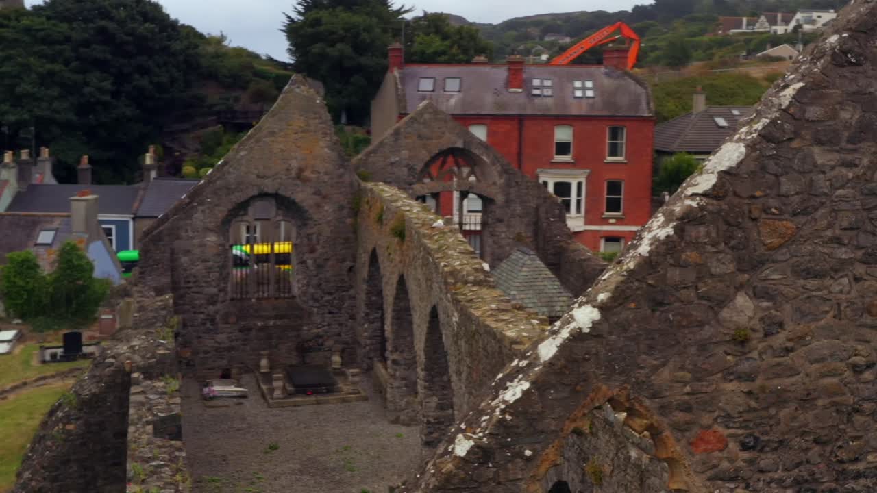 Pan across abbey wall ruins with moss and lichens growing off top of rocks, Howth Ireland