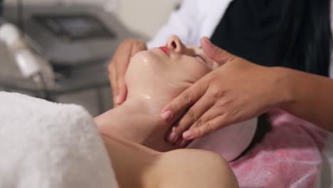 young woman is lying on the couch during cosmetic face procedure