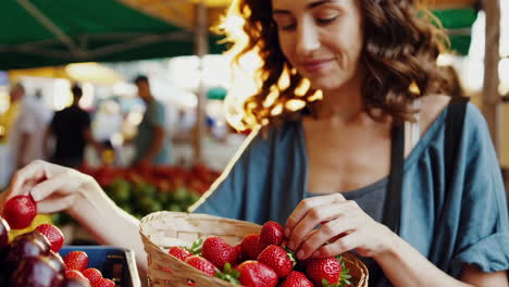 woman picking strawberries at a farmers market
