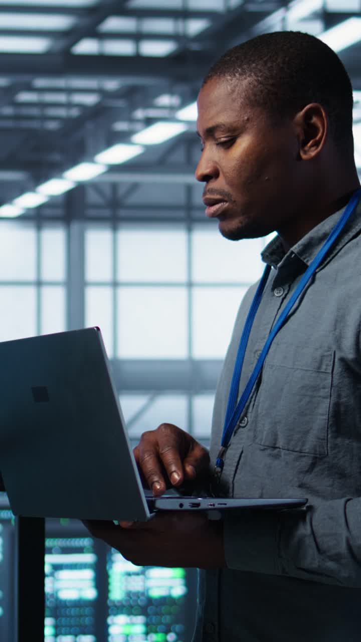 Vertical video Team of technicians working in server farm, using laptops to analyze data