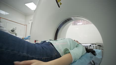 la paciente está siendo sometida a una tomografía computarizada o resonancia magnética bajo la supervisión de un radiólogo cualificado en una clínica médica moderna. la paciente está acostada en una mesa de tomografía computorizada o mri, moviéndose fuera de la máquina