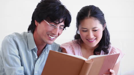 Couple-laughing-while-reading-a-book