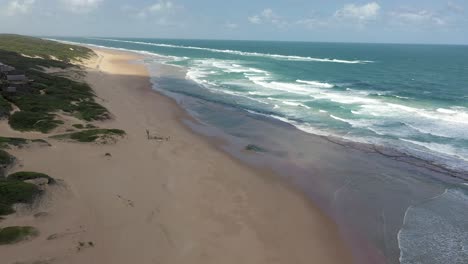 toma aérea panorámica de la inmensa playa de chidenguele en mozambique mostrando dunas y olas rompiendo