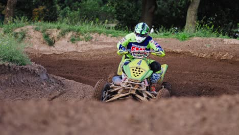 tracking shot of quad racer turning on dirt track during competition race in berlin