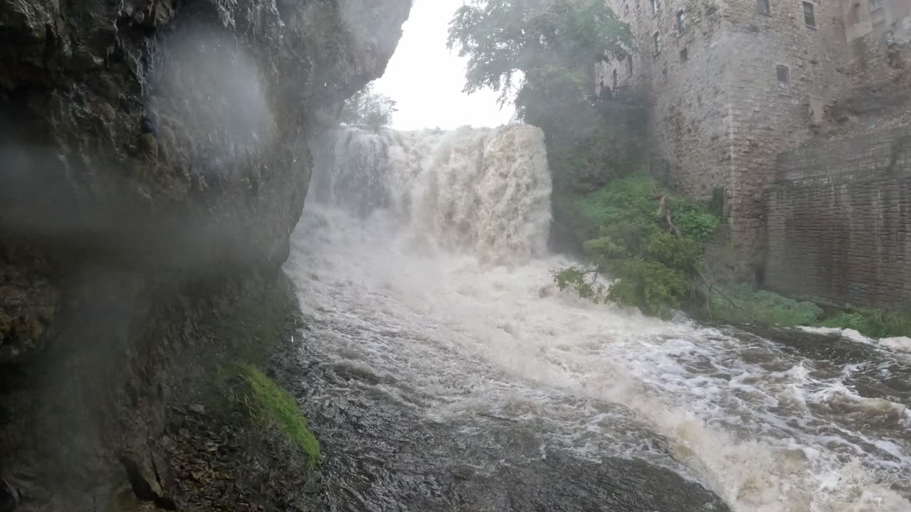 Rainy day and the waterfall falling intensely into the river