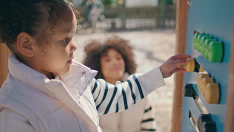 girl playing interactive board on playground closeup. mom watching child