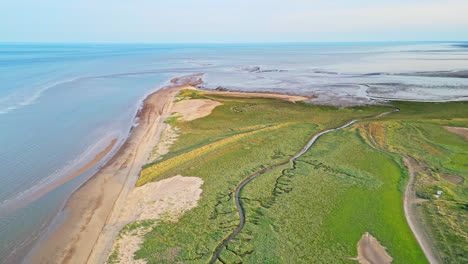 discover the idyllic charm of a golden hour coastal scene through breathtaking aerial drone footage: estuary, sandbanks, ocean, and marshlands