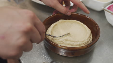 chef prepares mediterranean hummus starter dish