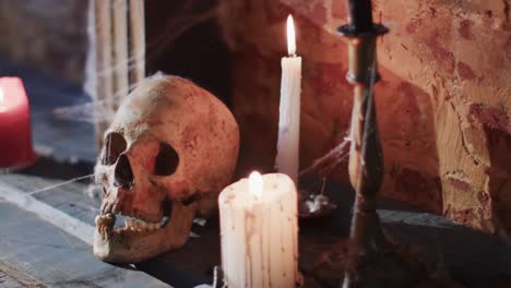 Video-Eines-Bücherstapels-Mit-Spinnennetz,-Totenkopf-Und-Kerzen-Auf-Backsteinmauerhintergrund