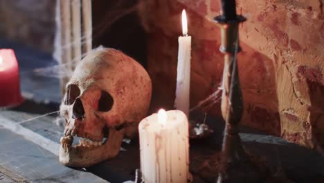 video of stack of books with spider web, skull and candles on brick wall background