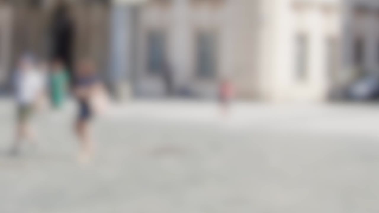 Unscharfe Aufnahme von Menschen, die Rad fahren und durch einen historischen Stadtplatz gehen.