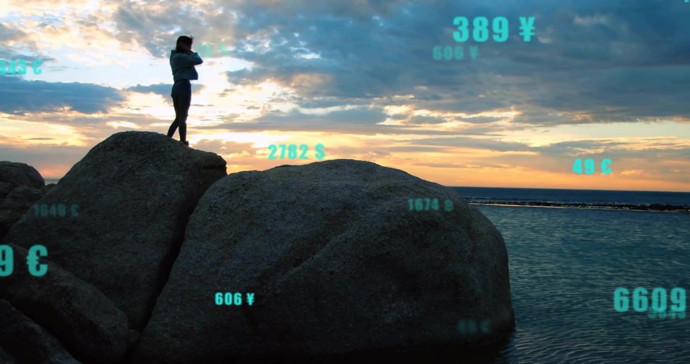 Woman climbing boulder at sea, scanning with smartphone and displaying AR finance and weather data