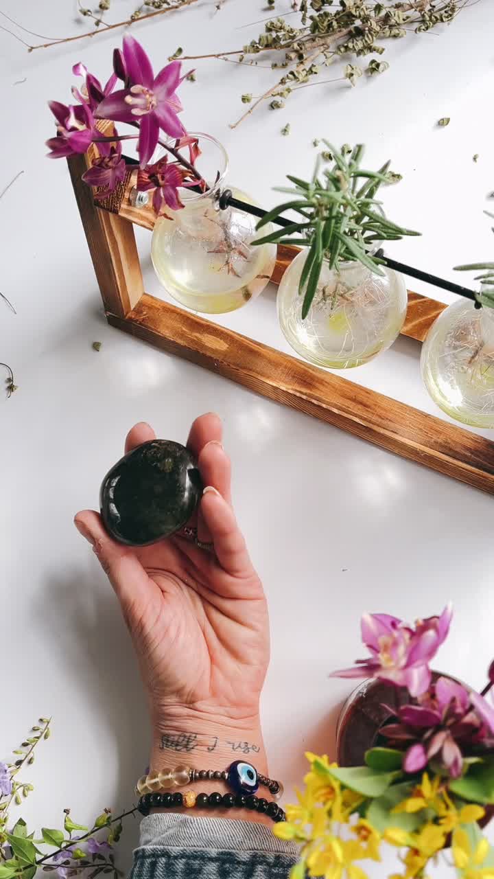 Hånd holder krystal med plante- og blomsterpynt