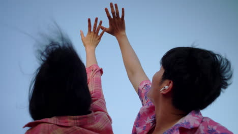 young-couple-reach-the-sky-holding-their-hands-together-in-love-during-their-summer-holiday-trip