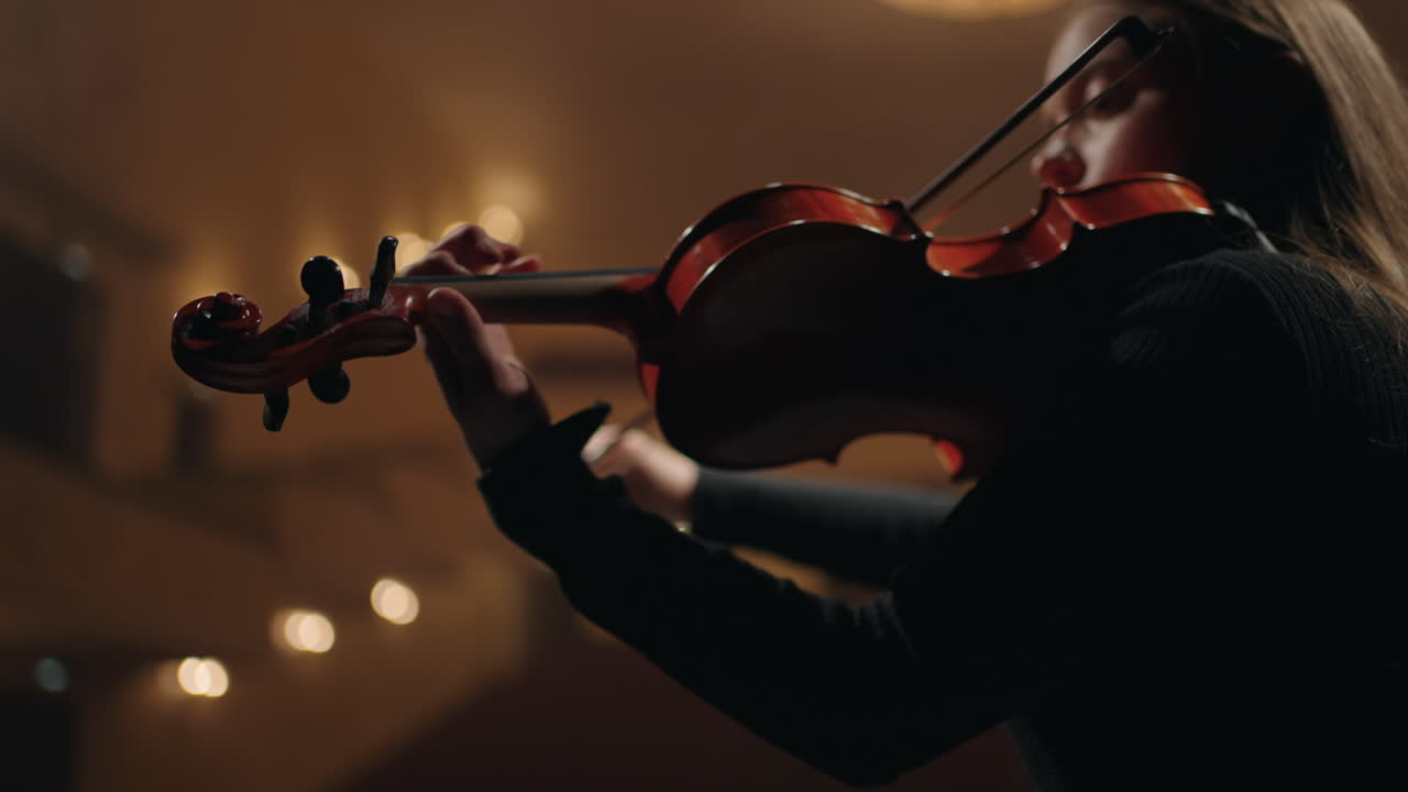 여성 바이올리니스트가 음악 학교에서 바이올린을 연주하고 있습니다. 여성의 손에 있는 바이올린의 클로즈업