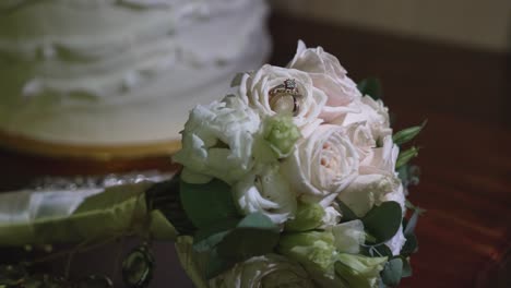 shiny wedding rings among white rose petals on the bride's bouquet