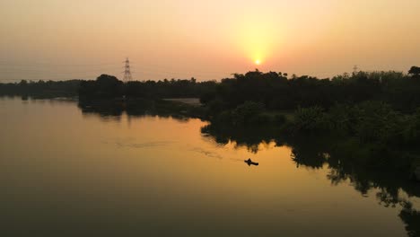 aerial view of a forest and river during sunrise, with vibrant colors spreading across the horizon.