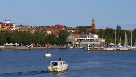 idyllic landscape of a boat cursing toward the historical harbor town on a sunny day in östersund sweden