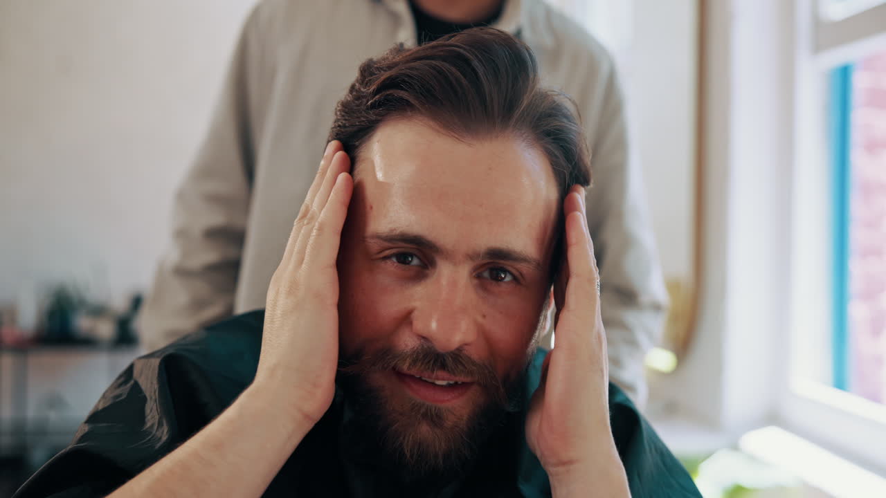 Glad mann sjekker sin nye hårklipp og skjegg i frisørsalongen