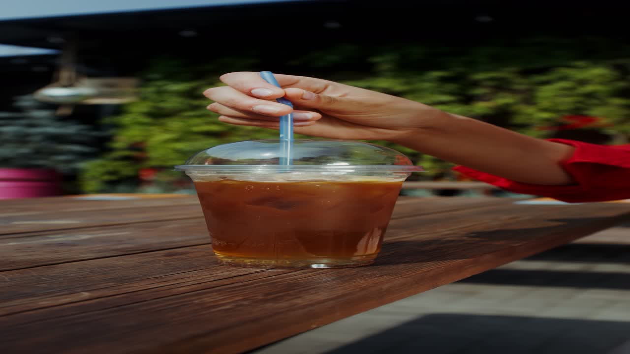 밖에서 얼음 커피를 마시는 여자