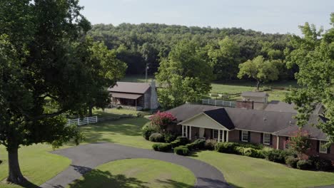 4k aerial of idyllic southern farmhouse with cabin and white fenced yard