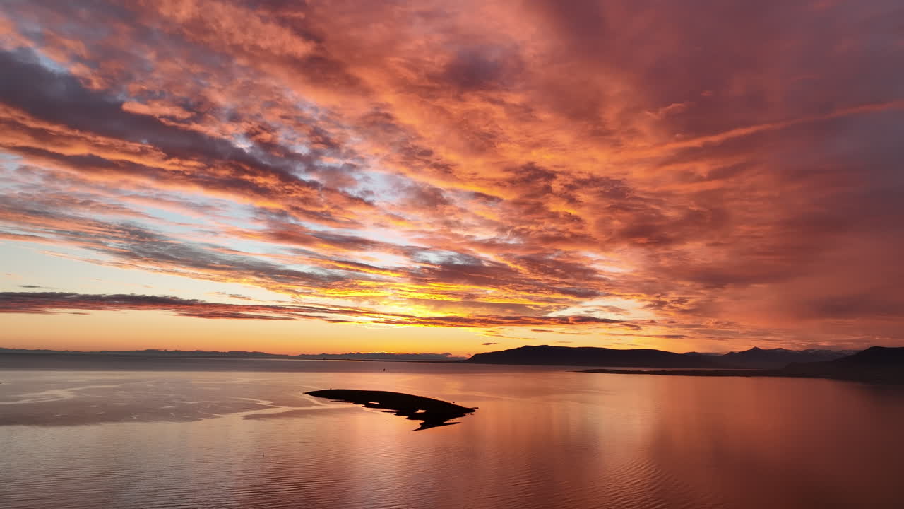 Luftfoto af smuk skyet solnedgang med orange og gul himmel over havet i Reykjavik