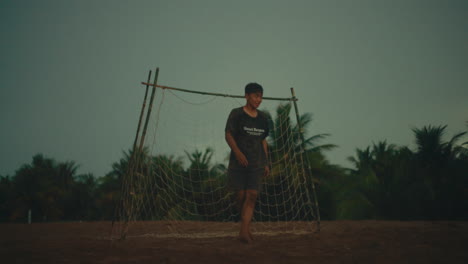 goalkeeper catching a football in slow motion on a sandy beach at sunset