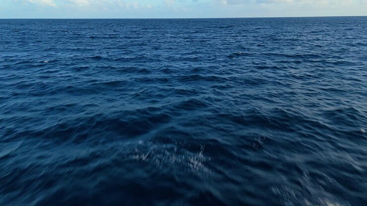 Ripresa aerea a bassa quota con dolly sopra le cime bianche e spumeggianti delle onde oceaniche, sfondo naturale