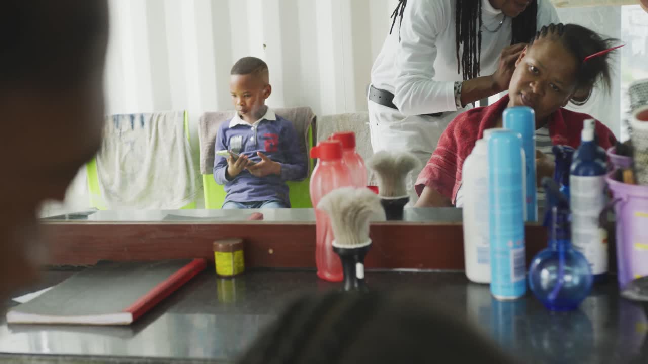 African woman at the hairdresser while boy waiting
