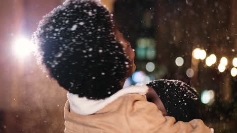 close-up view of joyful african american couple hugging and smiling while it¬¥s snowing on the street in christmas