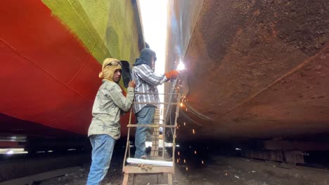 fixed shot of worker wearing protection mask welding old rusty boat, dhaka, bangladesh