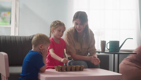 Girl-digs-holes-in-soil-with-mother-and-brother-at-home