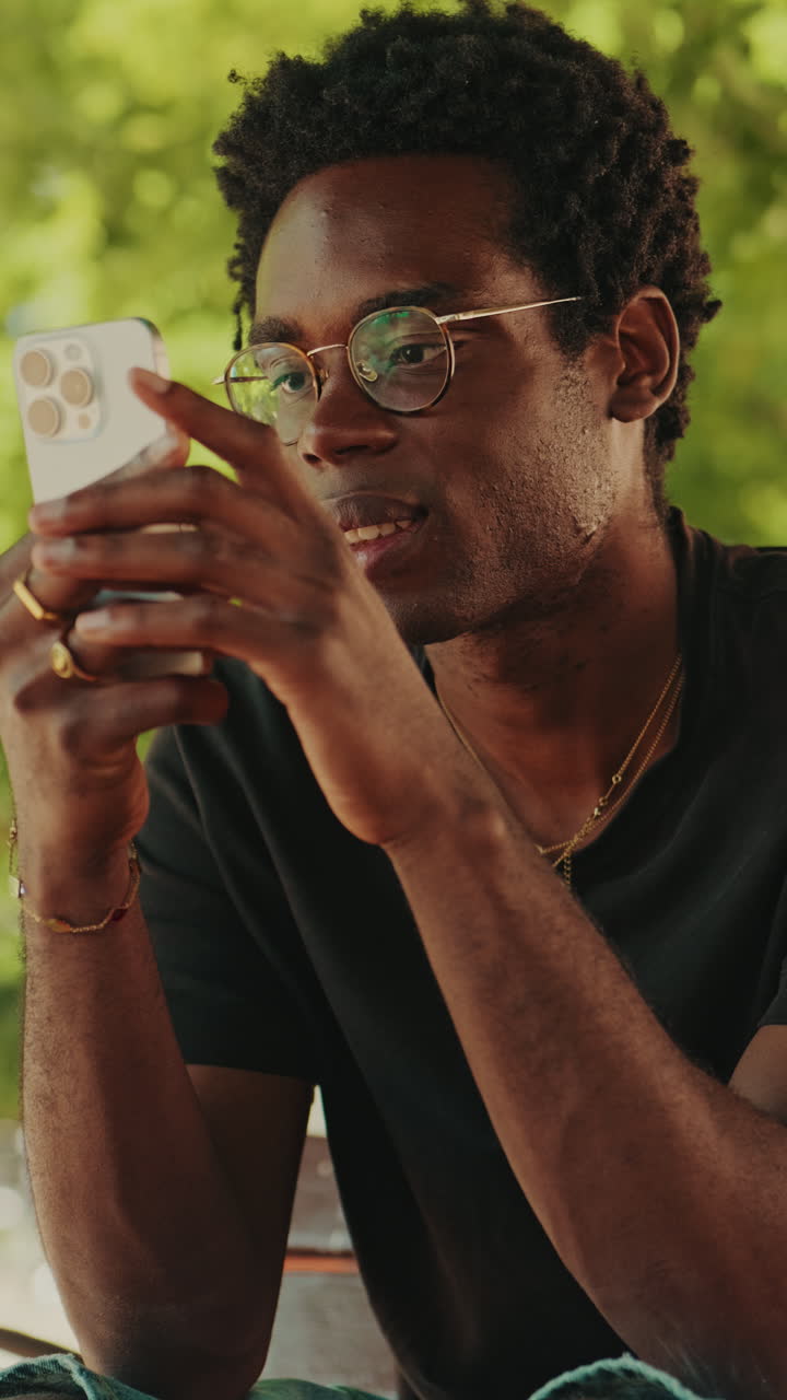 Young Black Man Using Smartphone Outdoors in a Park