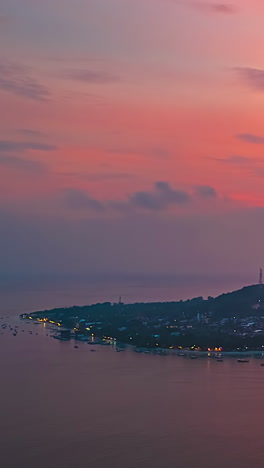 sunset to twilight time-lapse of bali coastline at dusk with warm orange glow in sky, vertical