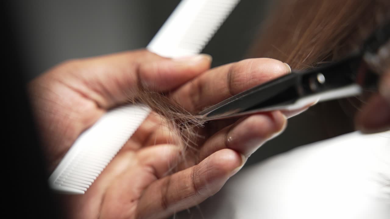 friseur schneidet dunkles haar mit einer schere