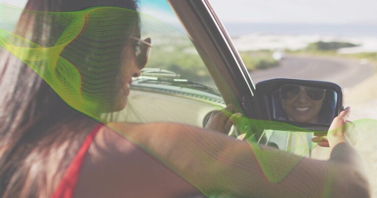 Happy Woman Driving Car and Smiling in Rearview Mirror