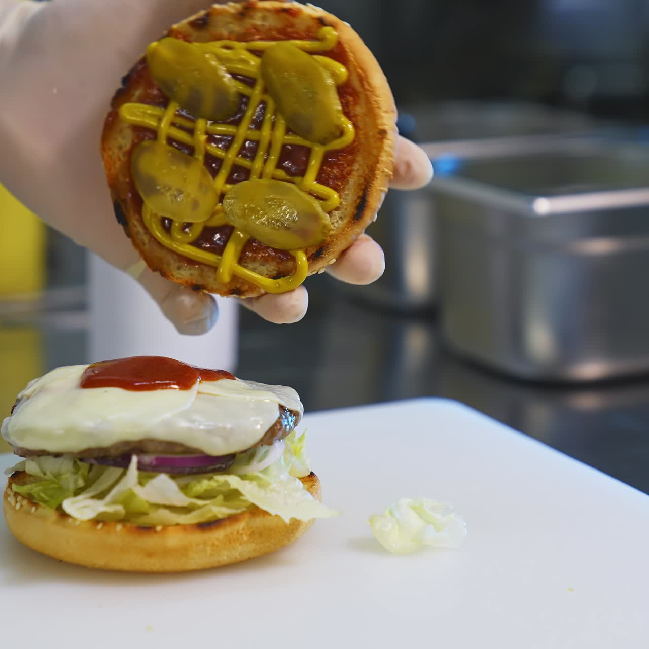 Making hamburger in fast food restaurant. Hand of man smears sauce on a burger and covers with fried bread. Close-up.Tasty burgery ready to eat