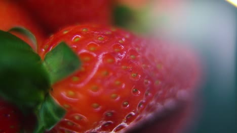 video macro detallado de una pila de fresas, fresa cruda roja gigante, hoja verde, en un soporte giratorio, movimiento suave, cámara lenta 120 fps