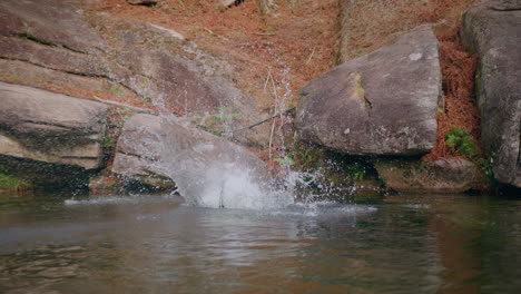 Niña-Se-Sumerge-En-El-Lago-Saltando-Desde-Una-Roca-Vista-Frontal-En-Cámara-Lenta