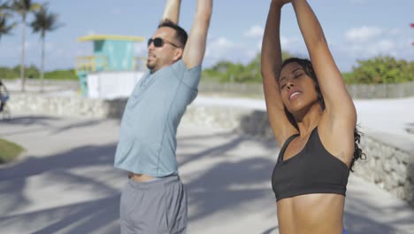 pareja deportiva estirándose a la luz del sol