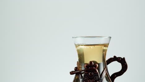 pouring tea from a glass teapot into a traditional glass