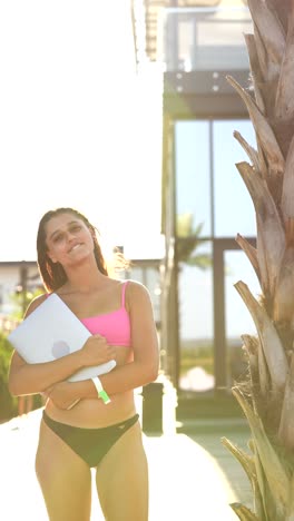 mujer en bikini con computadora portátil en un complejo