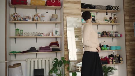 young woman looking in mirror and touching hair in small store