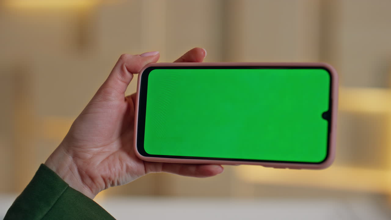 Freelancer hand tapping green screen cellphone in remote workplace close up.