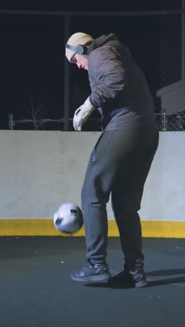 atleta realizando malabarismos de fútbol en una cancha al aire libre por la noche bajo luces brillantes, capturando precisión, habilidad y enfoque con fondo urbano, poste de portería sombreado y cancha amarilla vibrante